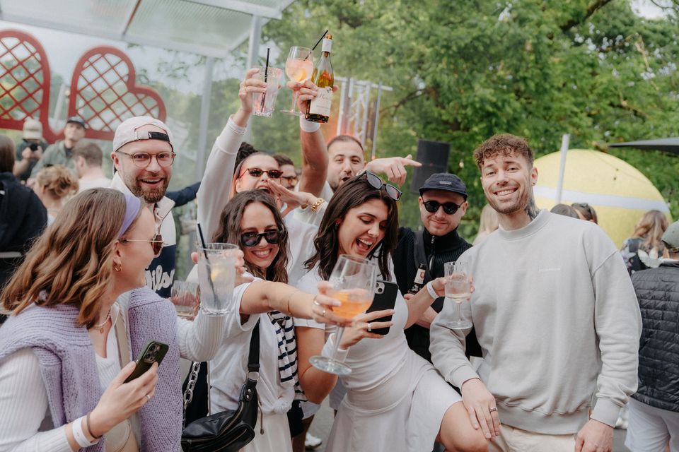 Freunde stoßen lachend vor Herzschlägern und Riesenball an