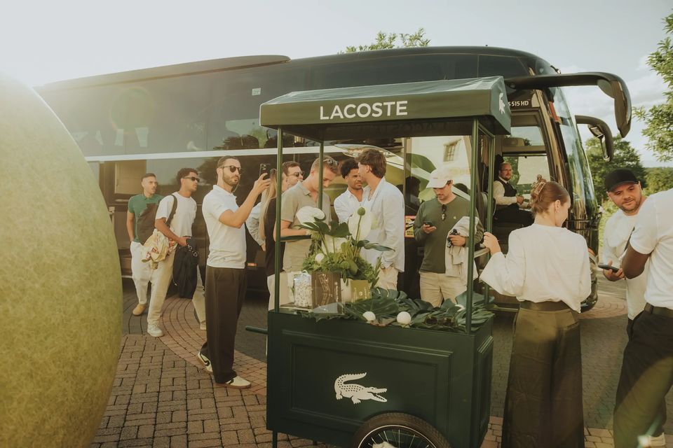 Gäste am grünen Lacoste-Wagen vor dem Shuttlebus