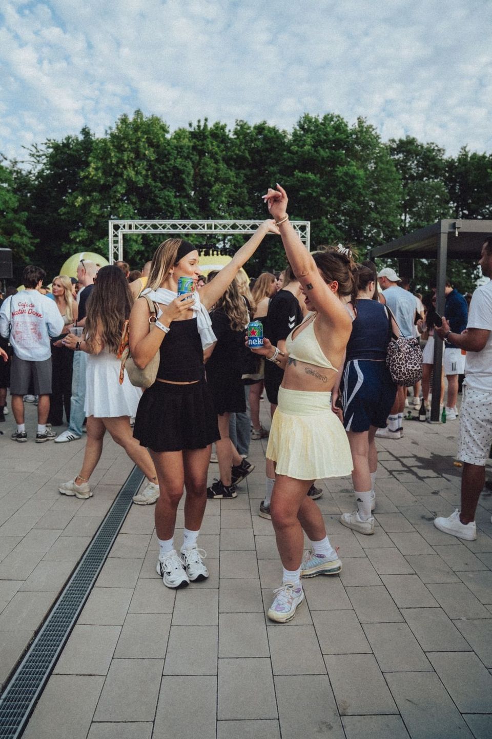 Zwei Frauen in Tennis-Outfits tanzen auf dem Platz vor der Bühne
