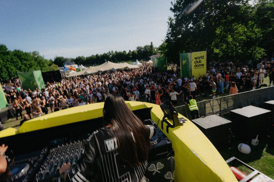 DJane am Pult der Fifteen Love Stage, vor ihr die sonnige, volle Wiese bis zu den Festivalzelten