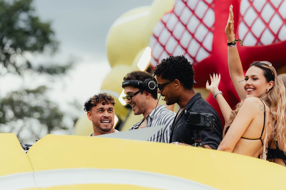 DJs und Gäste jubeln lachend am Ball-Pult vor dem roten Herzschläger